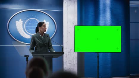 organization female representative speaking at press conference in government building with green screen mock up on display. press officer delivering a speech at summit. minister in congress.