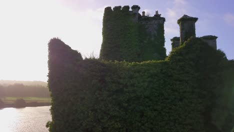 slow aerial pan captures menlo castle with ivy-covered top against the sun, revealing river corrib