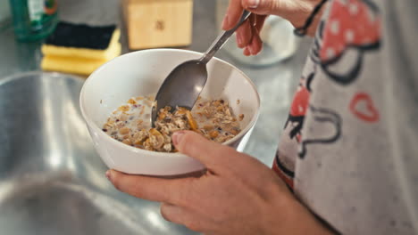 a woman in comfortable pajamas starts her day on a healthy note, preparing a delicious cereal, muesli breakfast