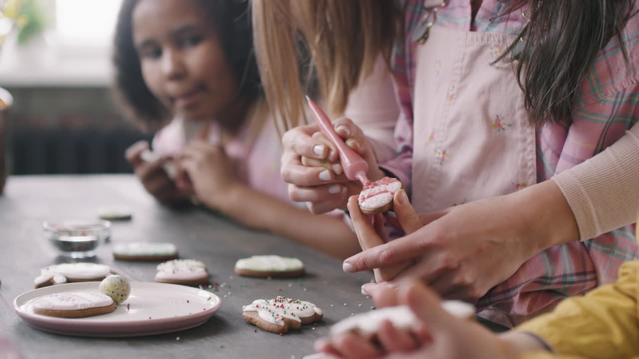Teacher or Parent Helping Girl Decorating Easter Cookie