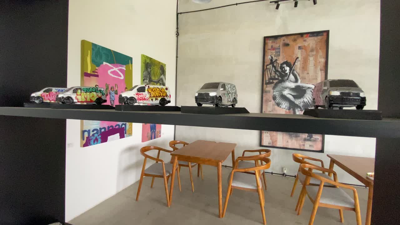 The footage shows the interior of a coffee shop displaying uniquely drawn miniature cars on the cupboard shelves.