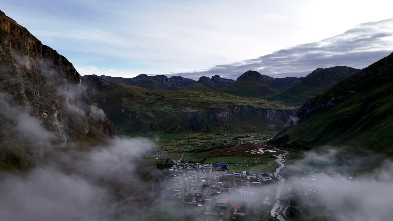 Cinematic aerial view of snowy Andes mountains in Peru with glaciers, rocky cliffs, and hidden blue alpine lake under misty clouds, dramatic landscape and natural travel destination