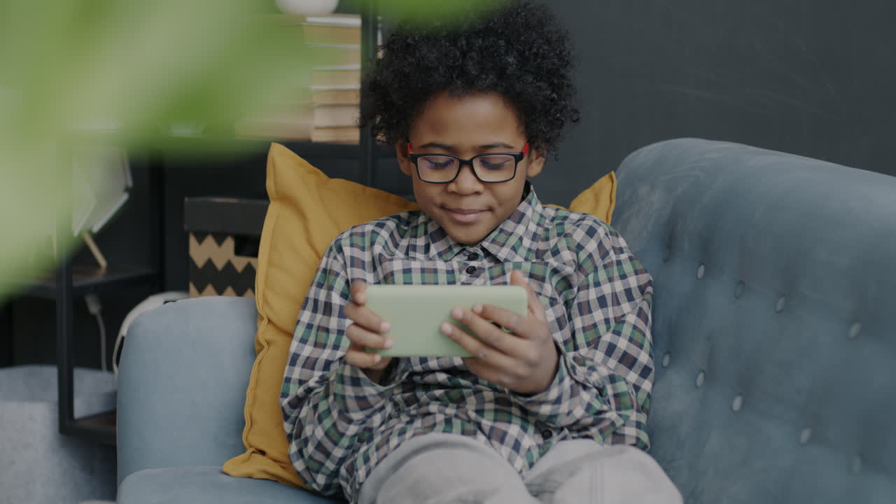 Boy Playing Game on Smartphone on Couch