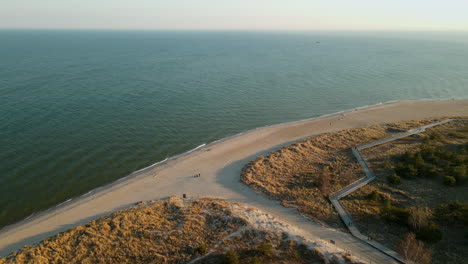 tourists on beachfront with coastal boardwalk in peninsula hel beach, baltic sea, poland