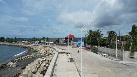 Vista-Aérea-De-La-Ciudad-Frente-Al-Mar-Y-Niños-Andando-En-Bicicleta,-Catanduanes,-Filipinas