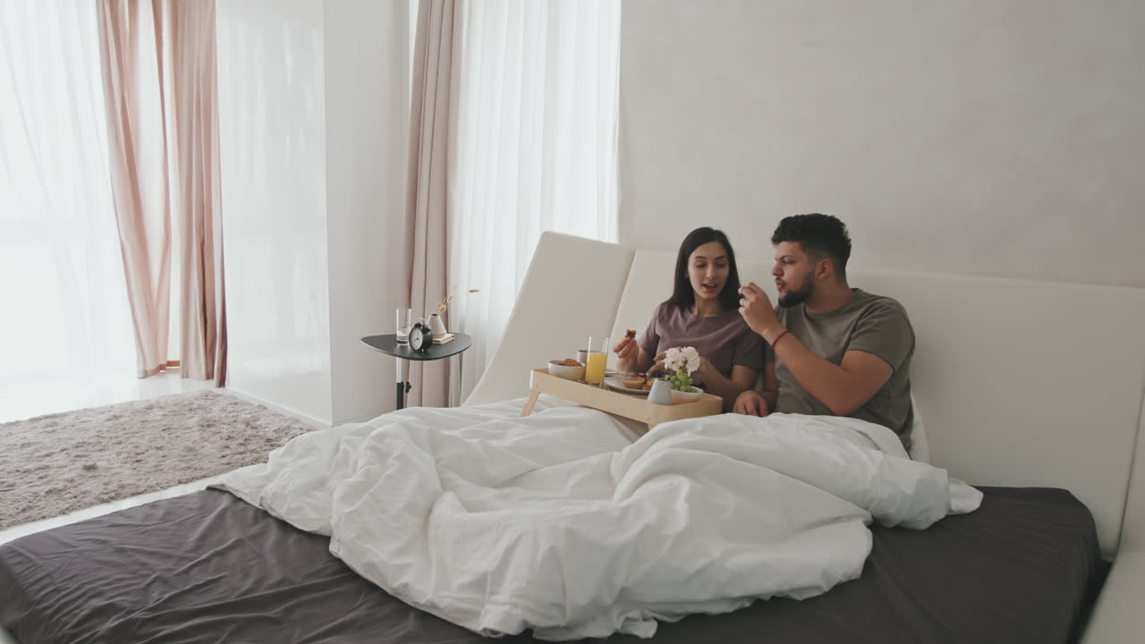 Latin Couple Chatting During Breakfast In Bed