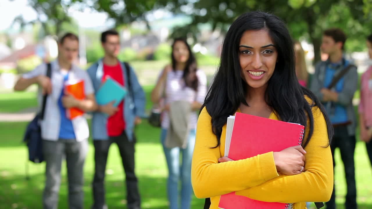 estudiante sonriendo a la cámara con amigos de pie detrás de ella