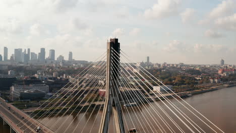 High-bridge-pillar-with-supporting-cables.-Close-up-of-modern-transport-infrastructure.-Cityscape-in-background.-Warsaw,-Poland