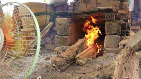 vista amplia baja del fuego de leña en el horno, el ventilador sopla fuego y humo, que ha vietnam hoi an