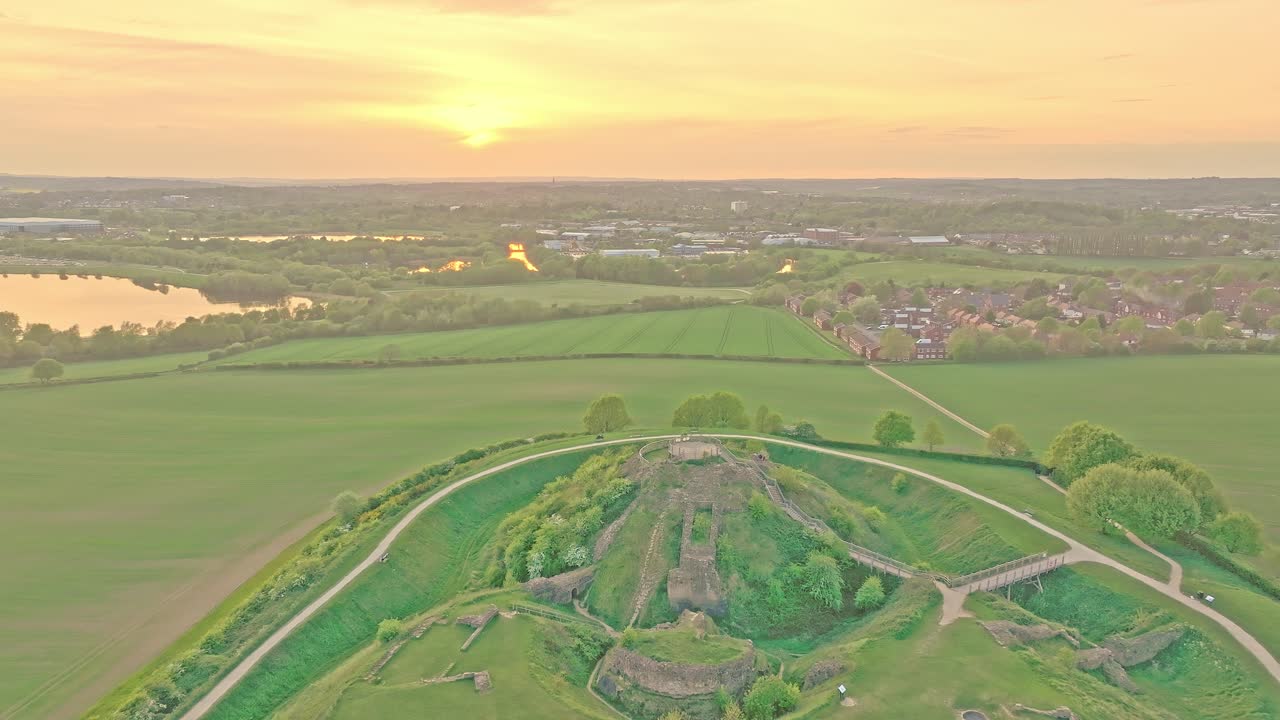 Ruined fortress walls visible among grassy ridges, aerial pullback, Sandal Castle Wakefield UK
