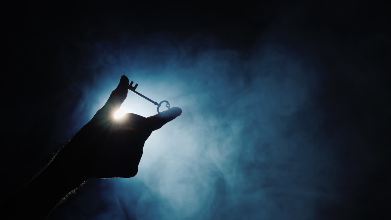 안개가 4k 비디오를 소용돌이치는 어두운 배경에 남자의 손이 열쇠를 쥐고 있다