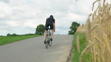 professional cyclist struggling to ride a bicycle uphill in countryside poland - tracking pan