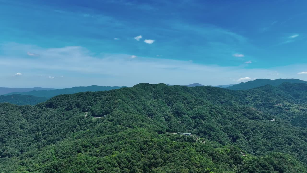 푸른 하늘에서 나무와 식물로 뒤 ⁇ 인 푸른 산의 풍경을 보여주는 영화적인 상승  ⁇