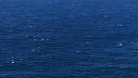 Wide-aerial-pan-of-wavy-open-blue-ocean-water