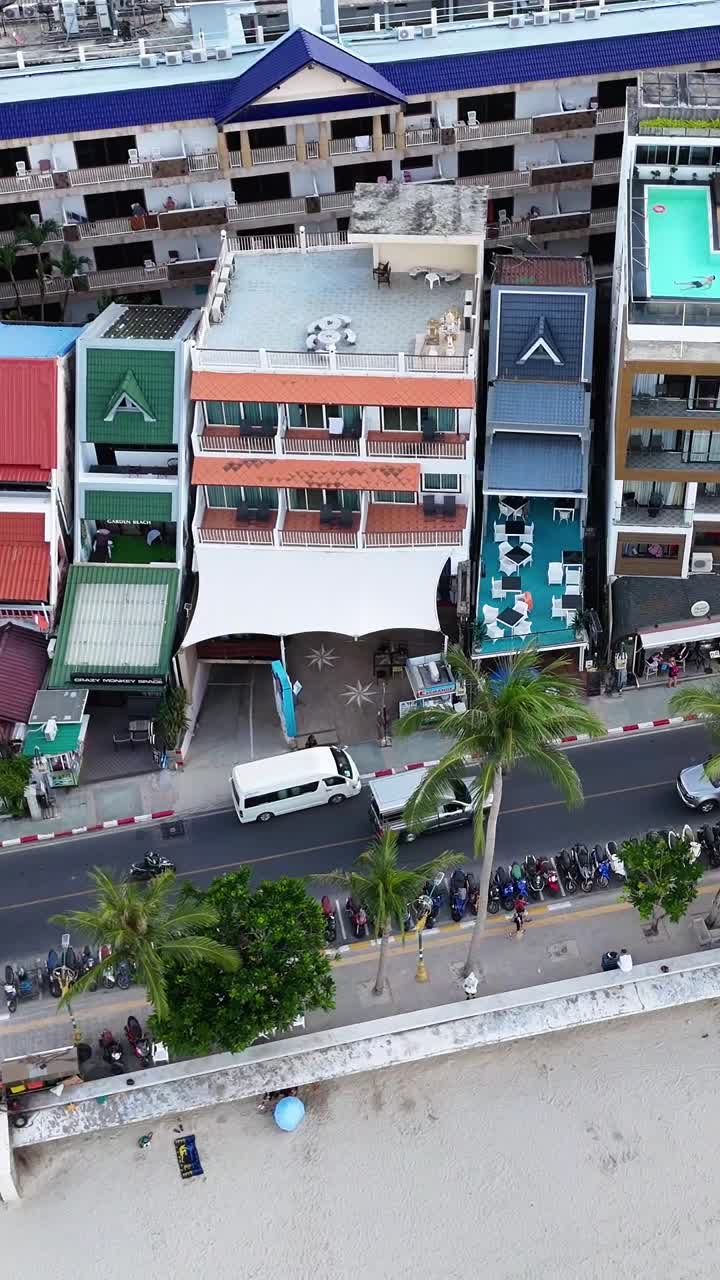 Aerial footage captures vibrant beachfront buildings and bustling street activity in Patong, Phuket, showcasing colorful architecture and lively atmosphere