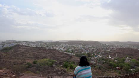 Aislar-A-Una-Chica-Viendo-El-Paisaje-De-La-Ciudad-En-La-Cima-De-La-Montaña-Con-Un-Cielo-Espectacular-Al-Atardecer.-El-Vídeo-Se-Toma-En-Mehrangarh-Jodhpur-Rajasthan-India.