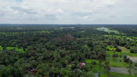 lush cambodian farmland gives way to temple ruins in the distance