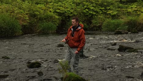 Hand-held-shot-of-a-fly-fisherman-casting-into-a-fast-flowing-river-in-Scotland