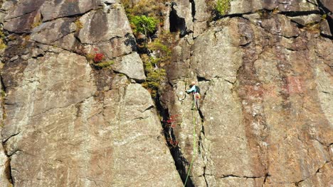 aerial footage lifting up past a lone climber on a cliff in maine