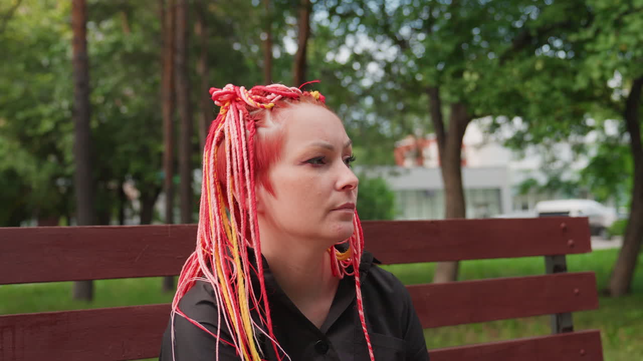 mujer bebiendo refresco, mujer con pelo de colores bebiendo una bebida, mujer reflexiva con trenzas bebiendo al aire libre, mujer serena con trenzas vibrantes haciendo una pausa para disfrutar de su refresco en la naturaleza