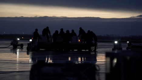 ground crew loading cargo on tarmac at twilight