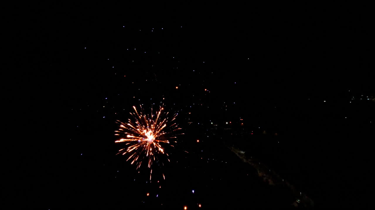 Spettacolo di fuochi d'artificio al rallentatore, esplosioni colorate nel cielo notturno, atmosfera festosa.