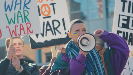 group of protestors with placards and megaphone on ukrainian anti war demonstration march