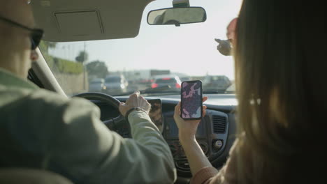 couple using smartphone with map in car