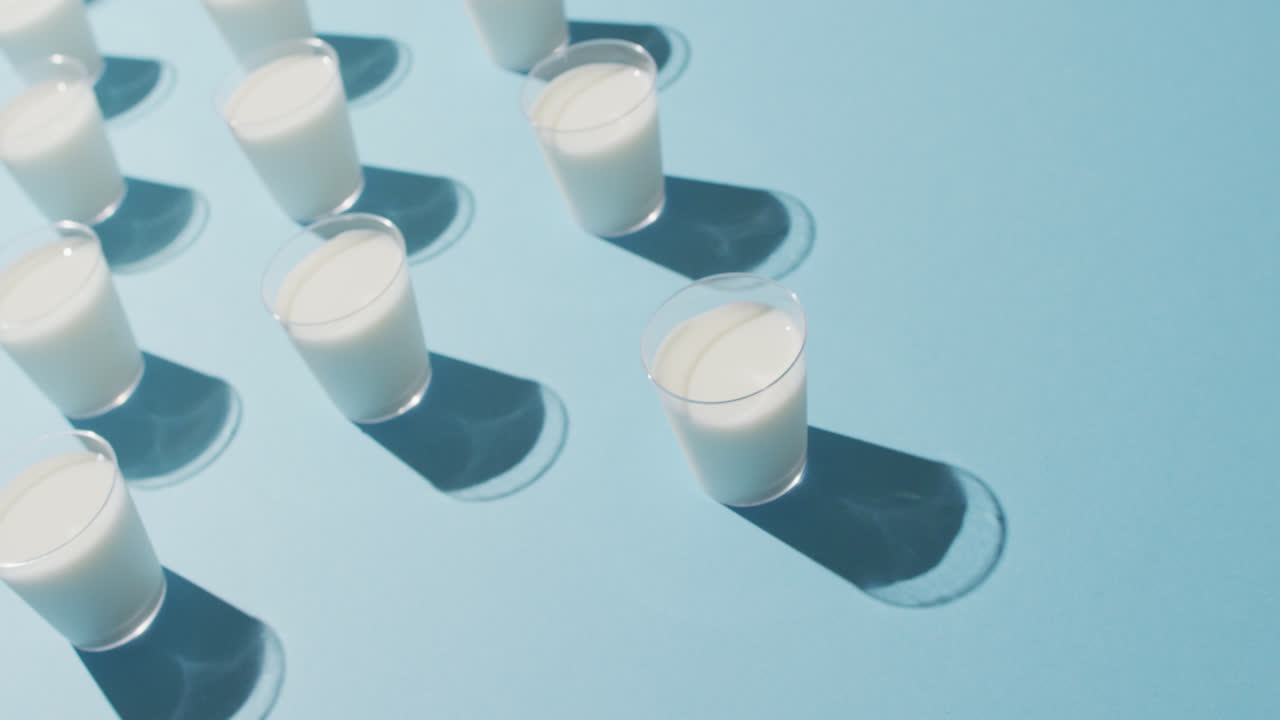 video de una fila de vasos de leche sobre un fondo azul