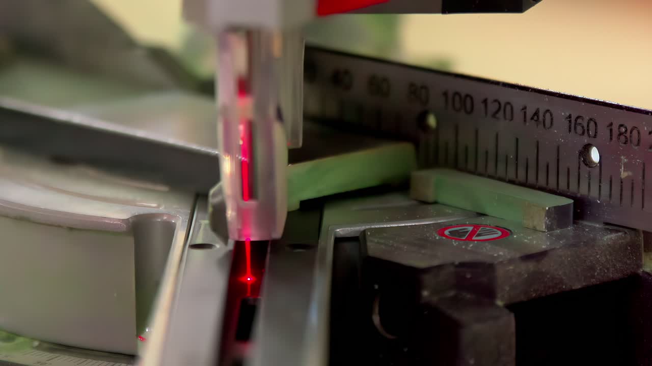 Eine Nahaufnahme eines Präzisionslaserschneiders, der auf einer Metalloberfläche arbeitet und von einer Messskala geführt wird. Die Szene hebt die Präzision und Technologie der industriellen Metallbearbeitung hervor.