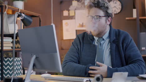 man smoking while working at a computer