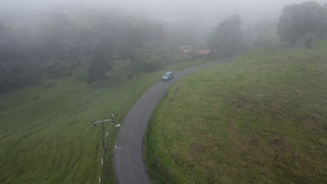 conducir a través de las montañas en un suv moderno, video aéreo, avión no tripulado, conducir en la montaña brumosa con vacas