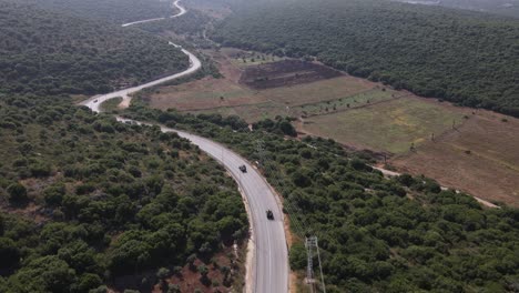 toma aérea cinematográfica de soldados del escuadrón del ejército de israel en vehículos que conducen a través de la carretera rural