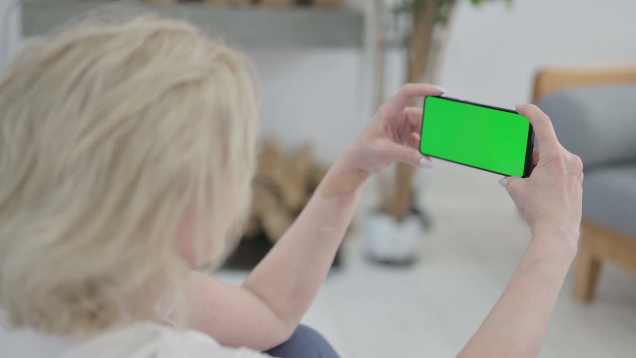 요가 매트 에 크로마 키 스크린 을 가진 스마트폰 을 사용하는 노인 의 뒷면