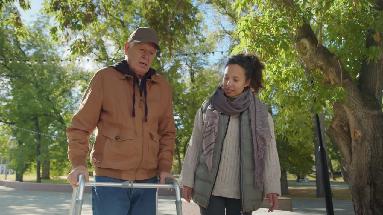 Elderly man with caregiver walking in the park