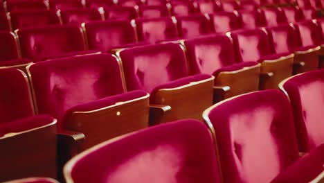 Dolly-to-left-over-endless-row-of-empty-red-velvet-theatre-seats