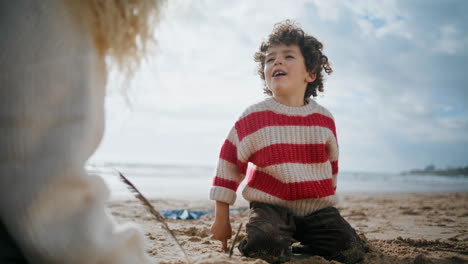 Little-boy-talking-beach-with-mother-on-cloudy-day.-Adorable-child-play-seashore