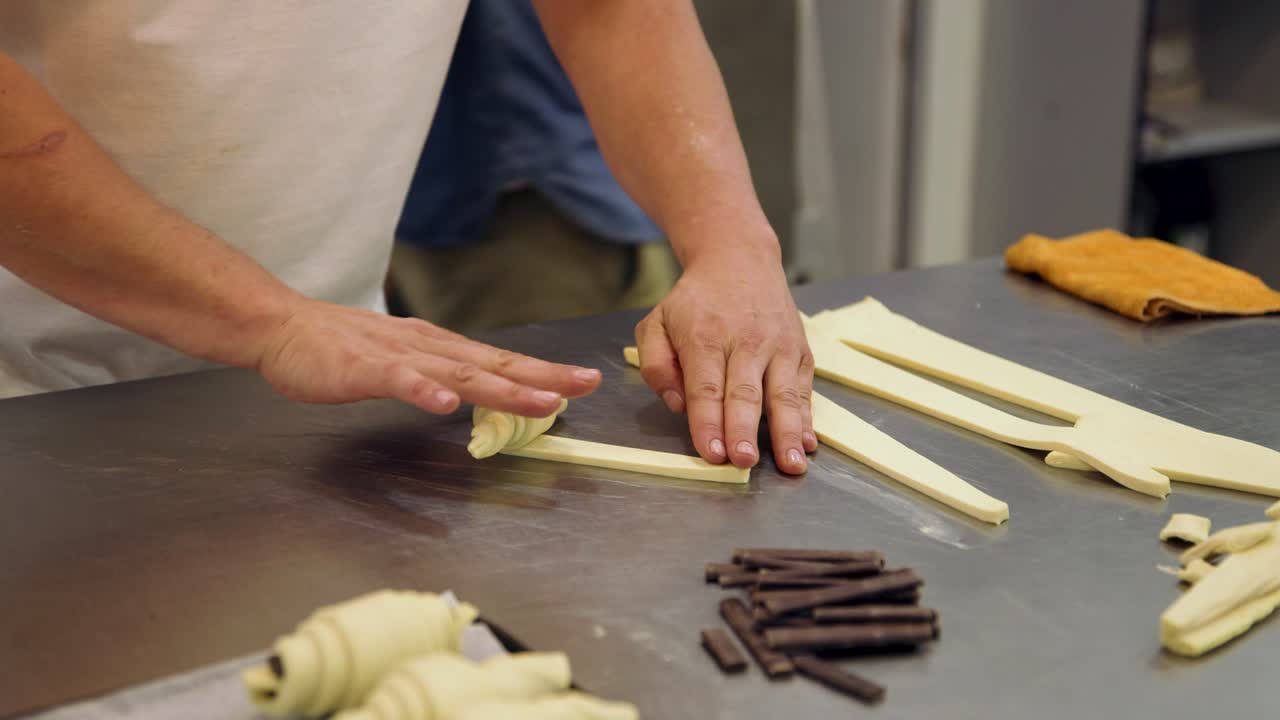 Hands of a Baker Rolling Dough to Form Croissants