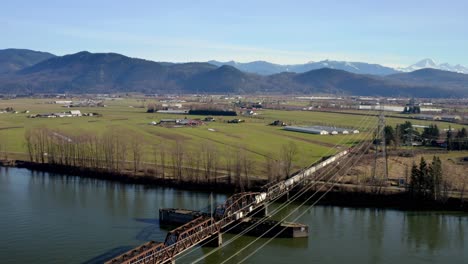 tranquil scene with rail bridge crossing a river in mission, british columbia, canada - aerial drone shot