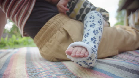 primer plano, concéntrese en los dedos de los pies de la pierna rota de un niño pequeño, sentado en mamá