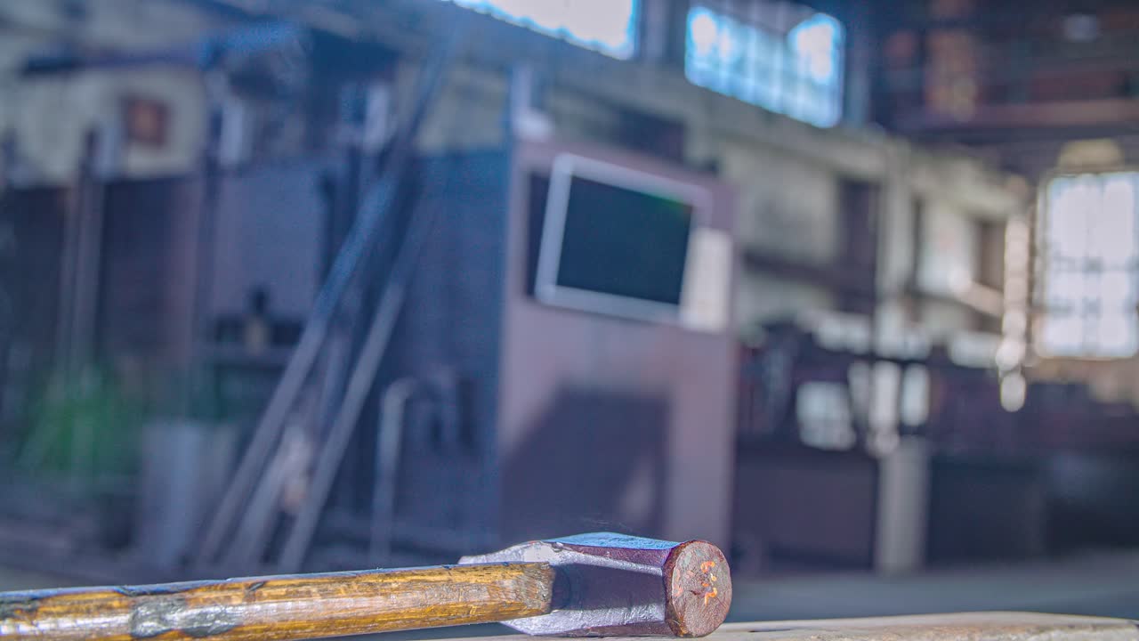 Blacksmith use large hammer hitting a metal surface, factory floor. Close up