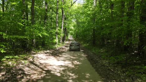 Vehicle-driving-on-back-road-of-Northern-Michigan,-aerial-follow-view