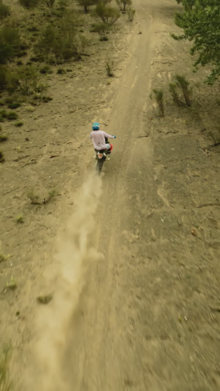 el motociclista sube a una colina polvorienta en una carrera de fpv. el deportista de motocross monta una poderosa motocicleta en las tierras altas escénicas. conquistando el desierto en un vehículo