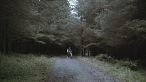 Young-man-runs-up-hill-in-forest-with-punctured-tire