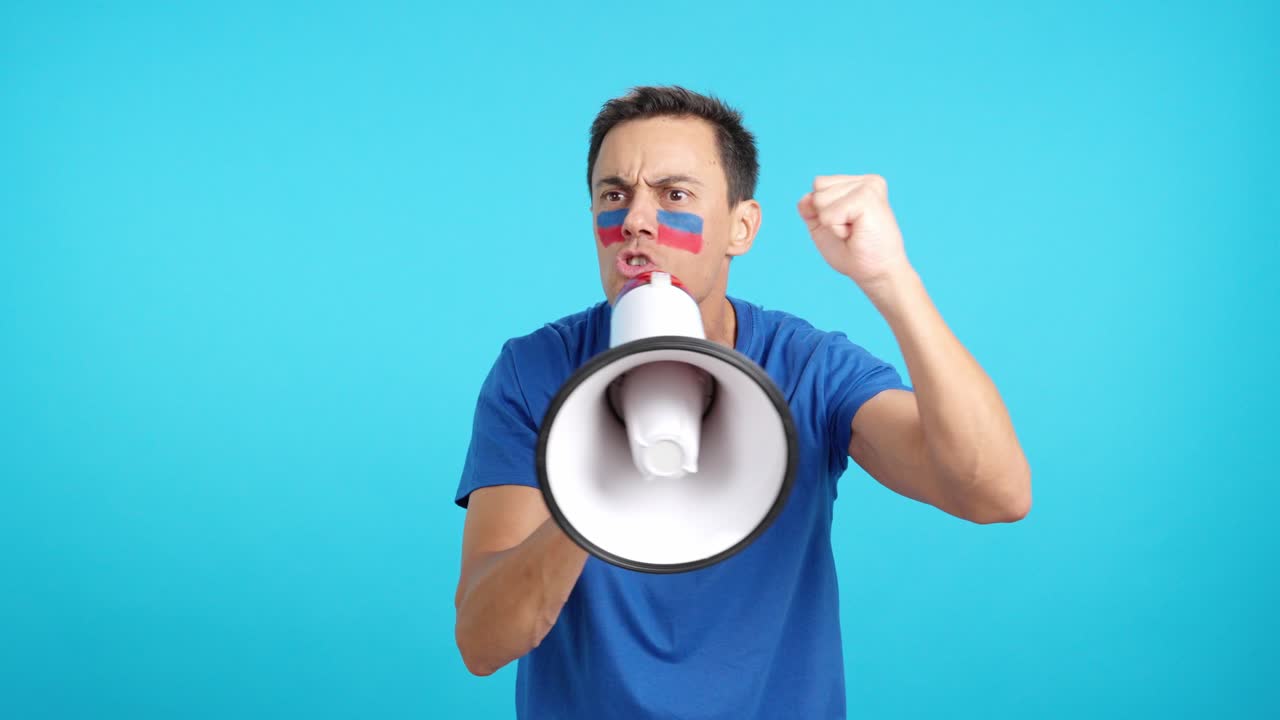 Excited man with haitian flag on face using a megaphone