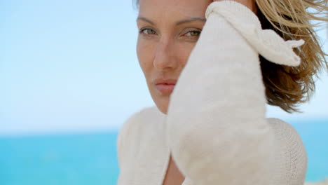 Mujer-Con-La-Mano-En-El-Cabello-Frente-Al-Océano-Azul