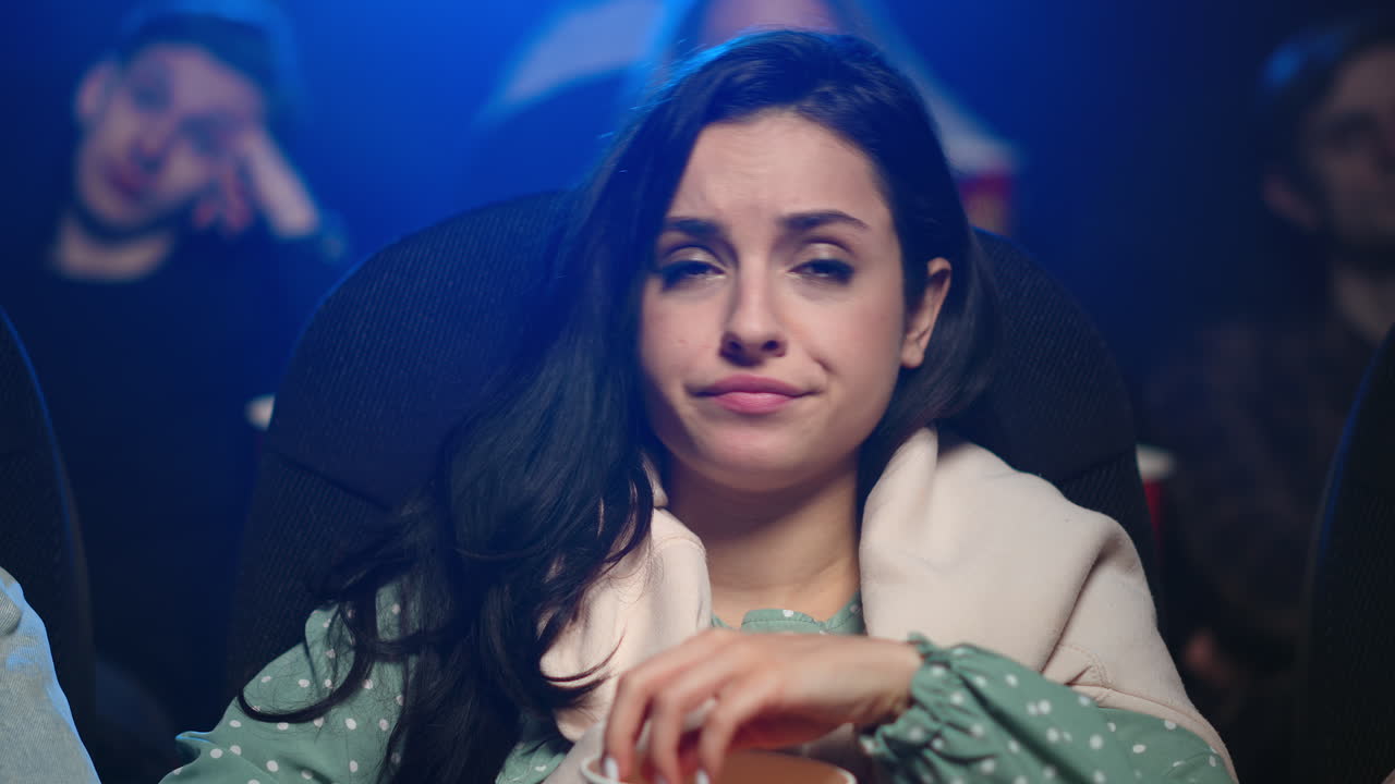 mujer molesta perdiendo tiempo en una mala película en el cine