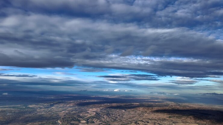 POV coinvolgente di un pilota dalla cabina di pilotaggio di un jet che vola sotto soffici e arrotondati strati nuvolosi in un cielo blu. Filmato aereo ripreso dalla cabina di pilotaggio di un jet. Scatto 4K ultrarealistico.