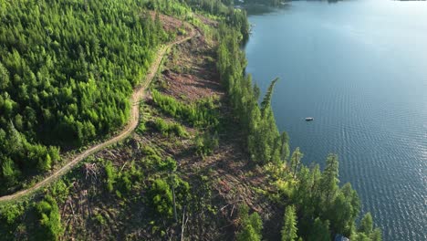 Drone-shot-of-a-dirt-road-along-the-edge-of-Spirit-Lake,-Idaho