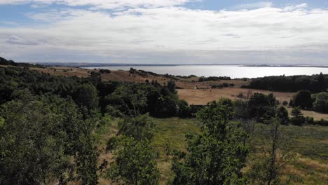 Aerial-view-of-the-coastline-of-Sejerøbugten-with-hills,-fields-and-ocean